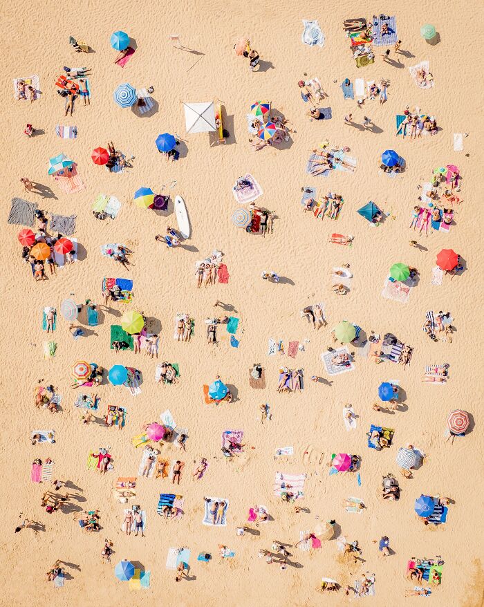 Aerial view of a crowded beach with colorful umbrellas, capturing a vibrant summer scene for Tokyo International Foto Awards.