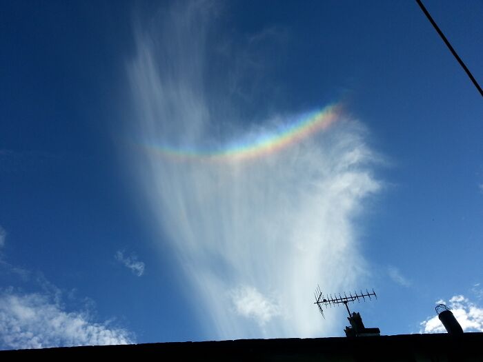 Colorful arc in the sky above a rooftop, showcasing stunning natural phenomena.