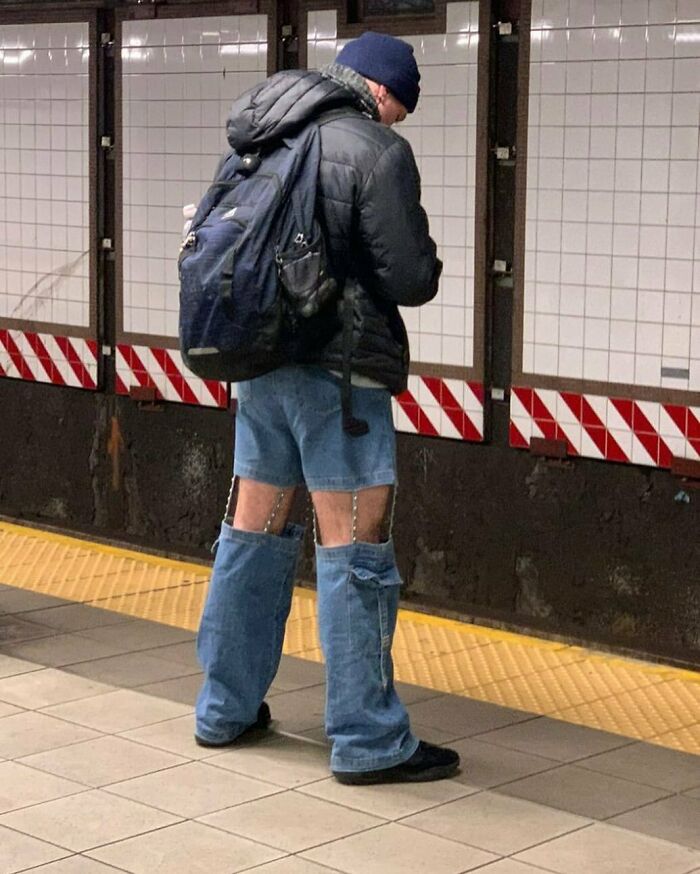 NYC local wearing unconventional fashion with jeans cut into chaps, standing on a subway platform.