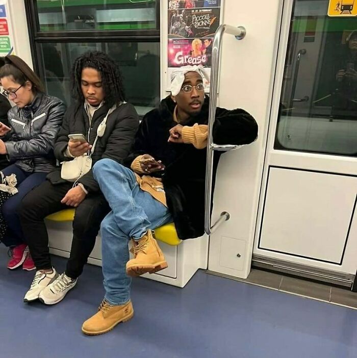 Three train passengers, one with a towel on their head, create a humorous scene in a subway car.