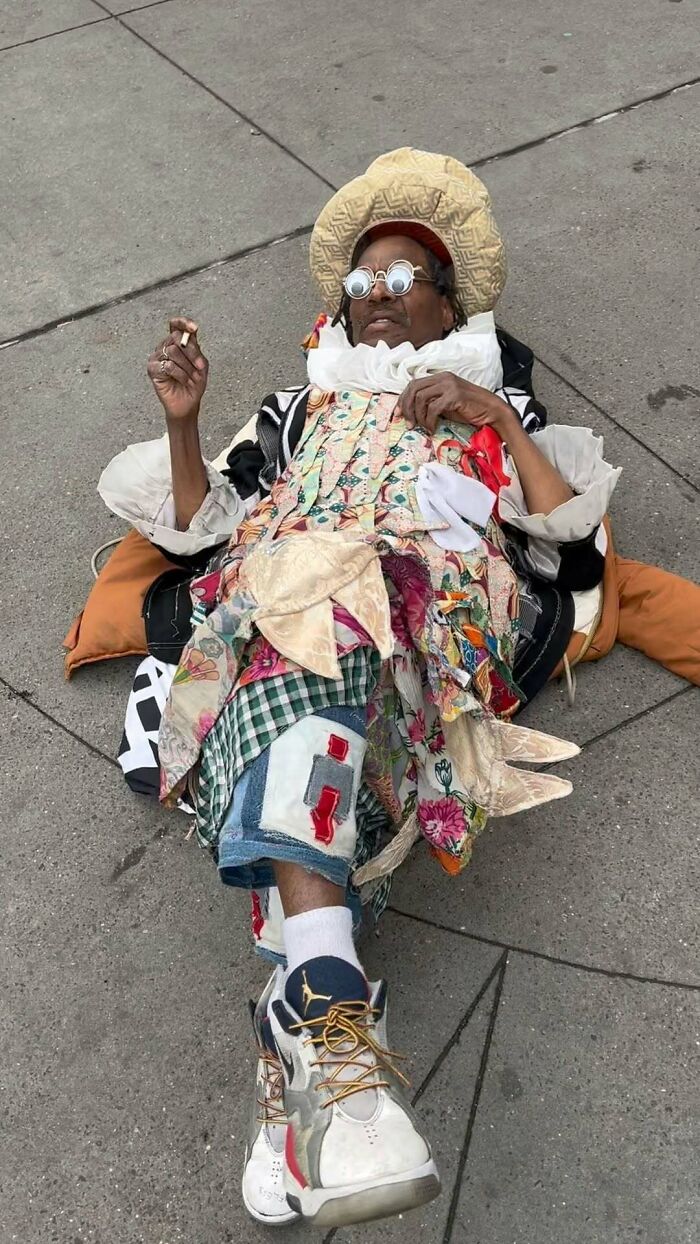 NYC local lying on pavement in eclectic, colorful outfit with layered patterns, showcasing bold fashion experimentation.