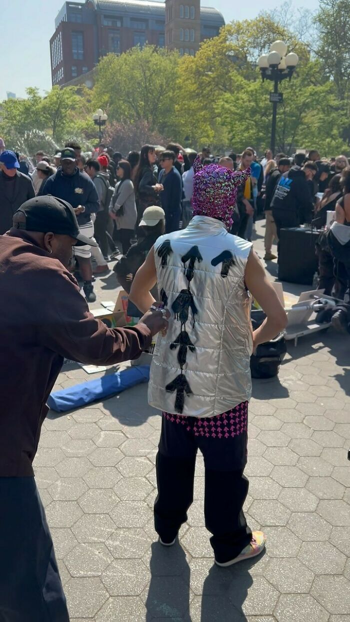 New York local wearing a colorful, eclectic outfit with a silver vest, in a crowded urban setting, expressing unique fashion.