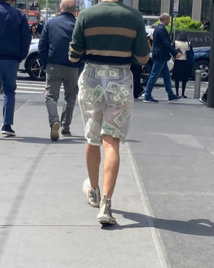 NYC local wearing experimental fashion with money-patterned shorts on a city street.