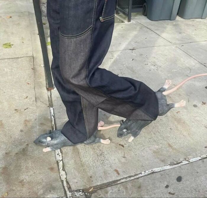 New York fashion: Person wearing jeans with unique rat-themed shoes on a sidewalk.