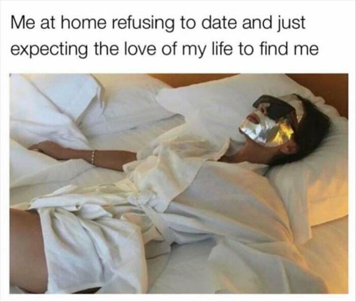 Woman relaxing in bed wearing a robe, facial mask, and sunglasses, humorously depicting dating expectations.