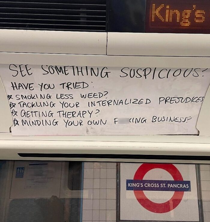 Handwritten sign in King's Cross tube advises minding your own business; British humor.