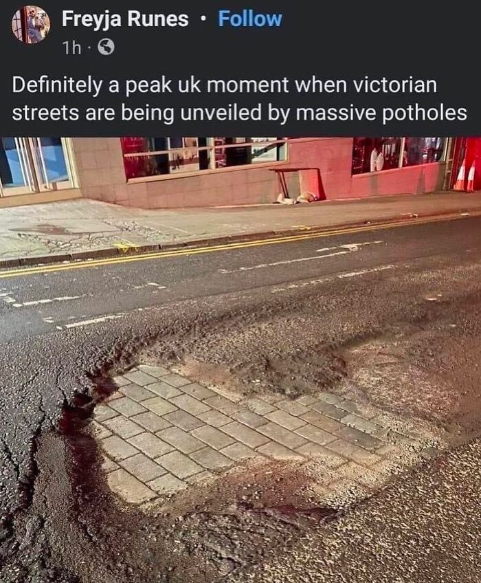 Massive pothole revealing Victorian cobblestones on a UK street at night.