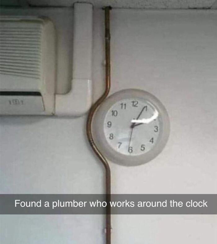 Plumbing pipe humorously circles a wall clock next to an air conditioning unit, showing British wit.