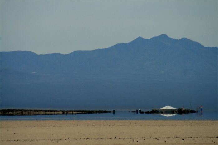 Desert mirage creating an illusion of water with mountains in the background, illustrating natural phenomena.