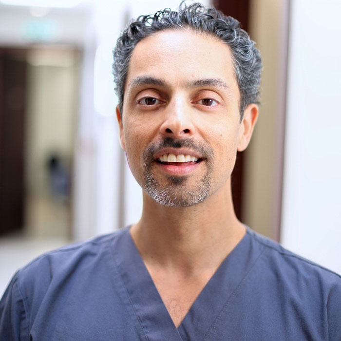 A person in scrubs smiling indoors, associated with science and beauty analysis.