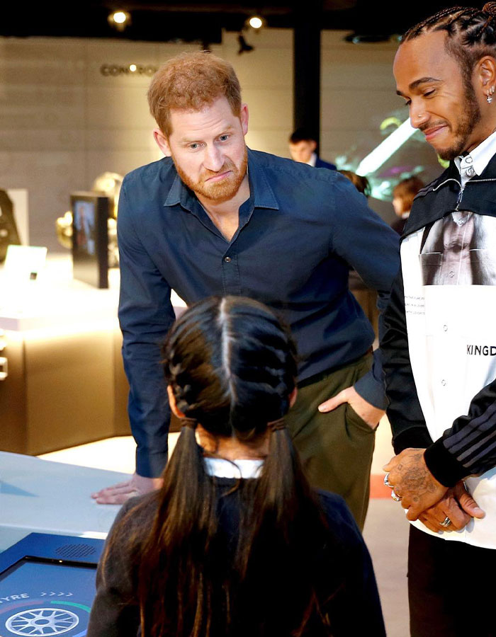 A man in a blue shirt and another man talking to a child at an event.