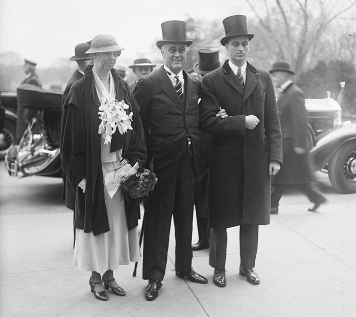 Past First Ladies’ inauguration attire with group in formal wear and vintage cars in the background.