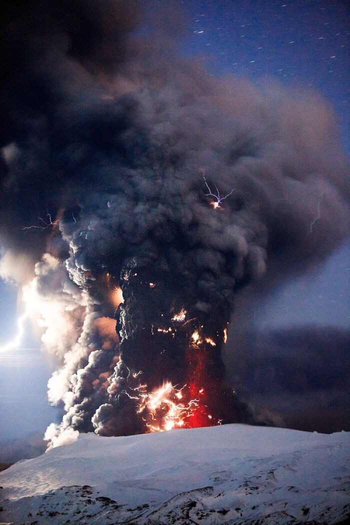 Volcanic lightning and smoke erupting, showcasing incredible and stunning natural phenomena against a night sky.