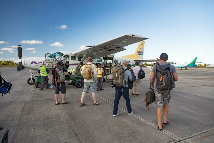 People boarding a small plane at an airport, embarking on a journey to a remote island in Belize.