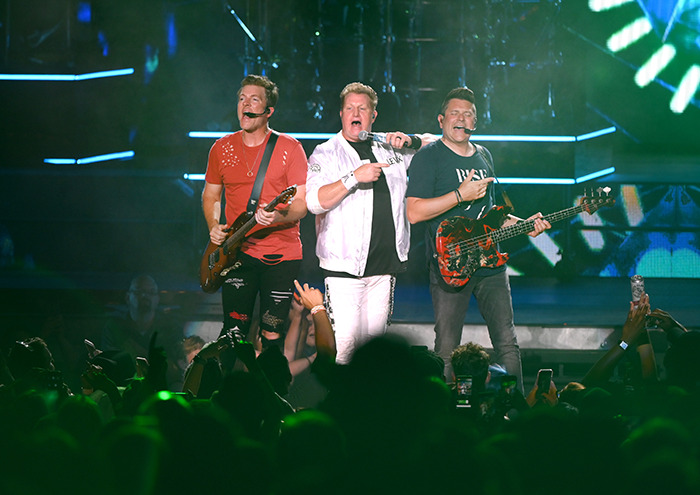 Musicians performing on stage with guitars and microphones during the inauguration event.