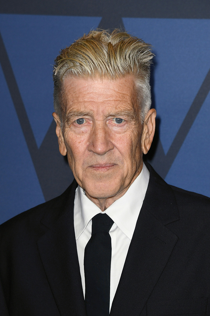 Man in a suit with a solemn expression against a dark background.