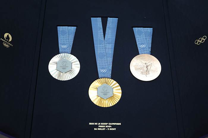 Paris Olympic medals display against a dark background.