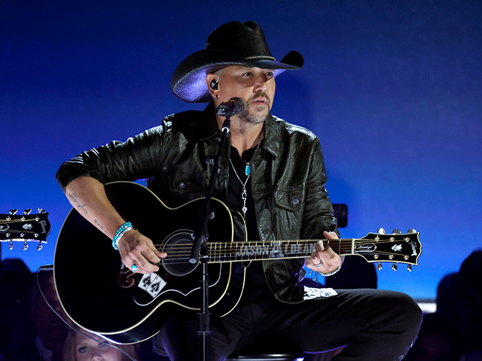 Musician in black hat performing onstage with guitar at inauguration event.