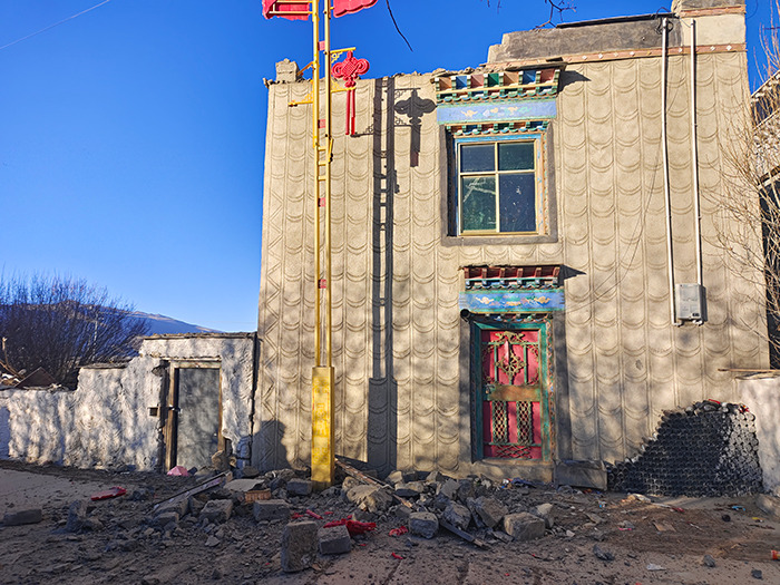 Damaged building after 7.1 earthquake, rubble scattered on the ground.