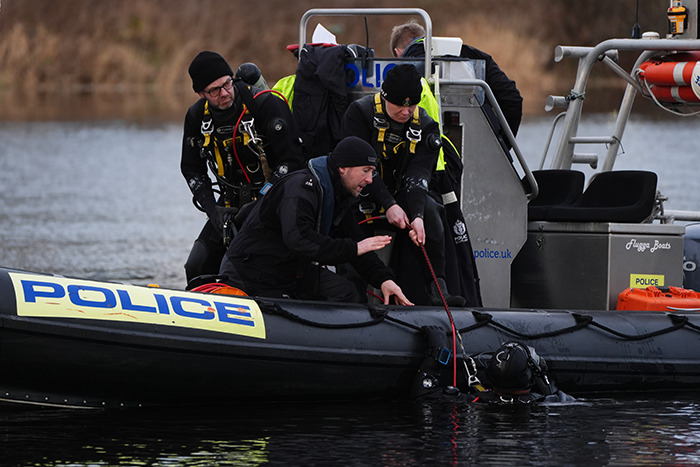 Police divers on a boat conducting a search for missing sisters after their disappearance.