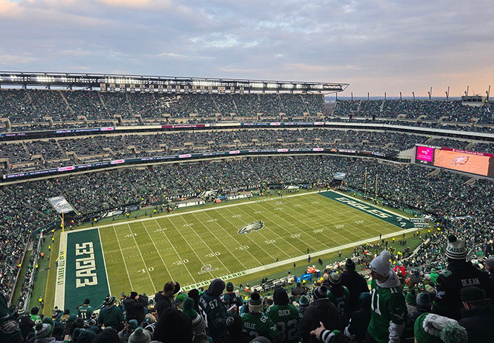 Eagles fans at a crowded stadium during a game, with the field and stands visible, showcasing fan enthusiasm.