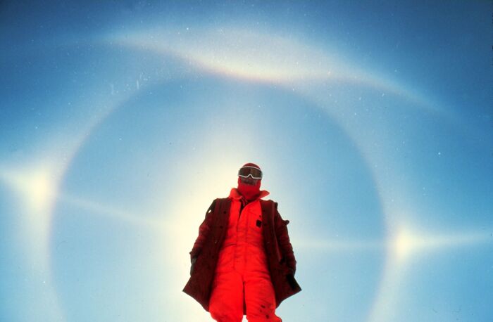 Person in red suit under a halo in the sky, showcasing natural phenomena.