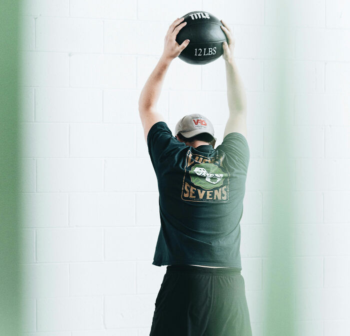 A person lifting a 12-pound medicine ball.