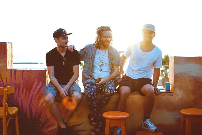 Three friends sitting together outdoors during sunset.