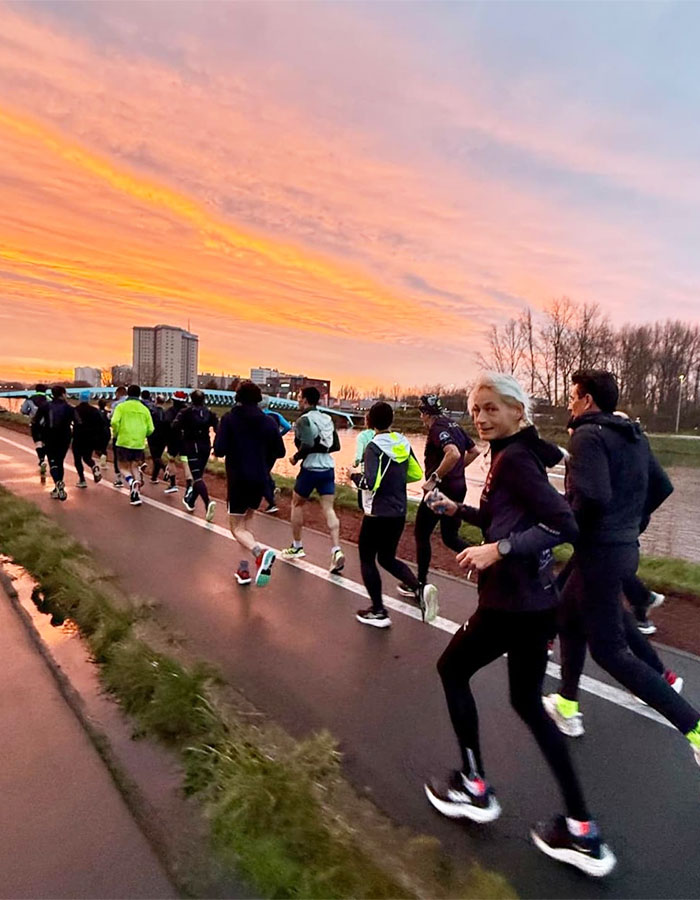 55-year-old woman running marathon with group at sunset, showcasing a world record achievement.