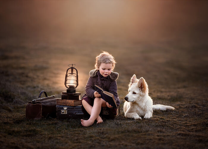 Child reading with dog in serene setting, celebrating International Pet Photographer Of The Year Awards.