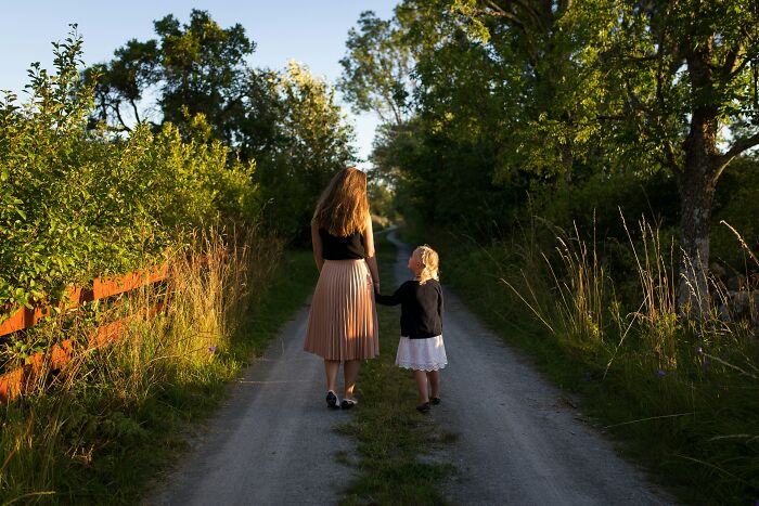 Woman and child walking on a country path, surrounded by trees, suggesting family happiness in marriage.