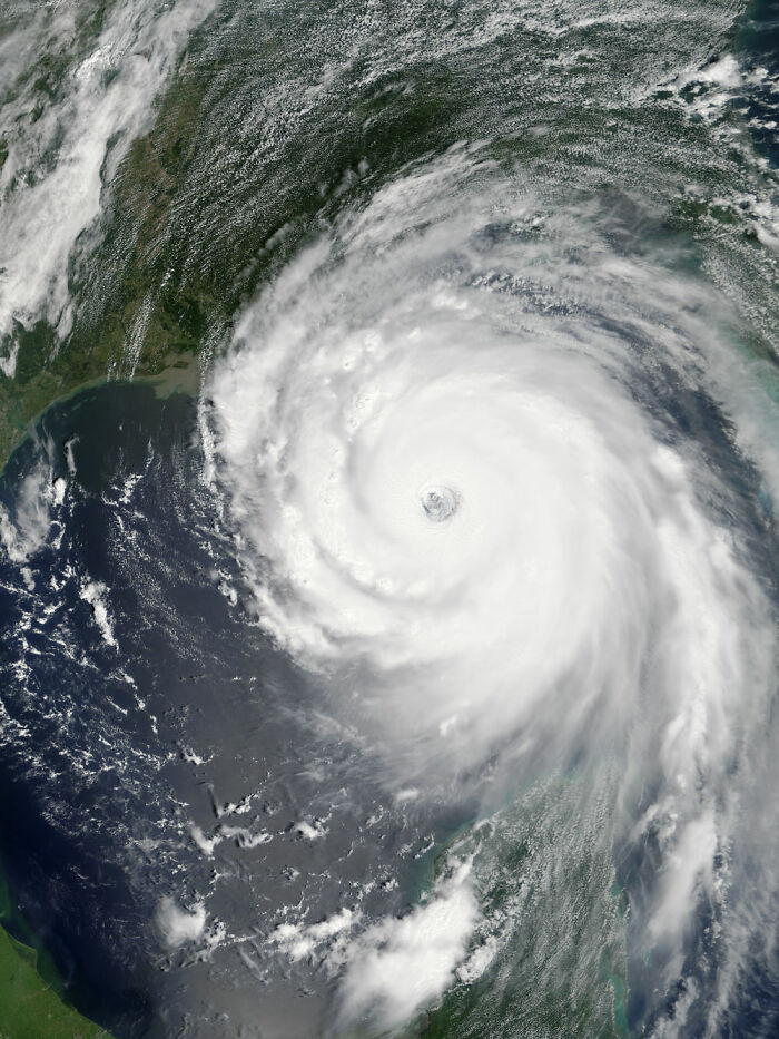 Satellite view of a large hurricane forming over the ocean, with swirling clouds and visible eye of the storm.