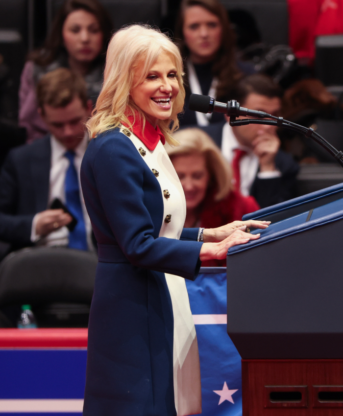 Woman in a controversial outfit at a podium during the presidential inauguration, wearing a blue and white coat.