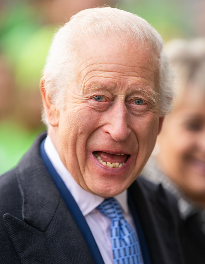 Elderly man in suit smiling widely outdoors, highlighting UK dentist shortage issue.