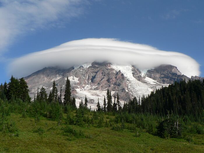 Lenticular cloud over a mountain peak, showcasing stunning natural phenomena against a clear blue sky.