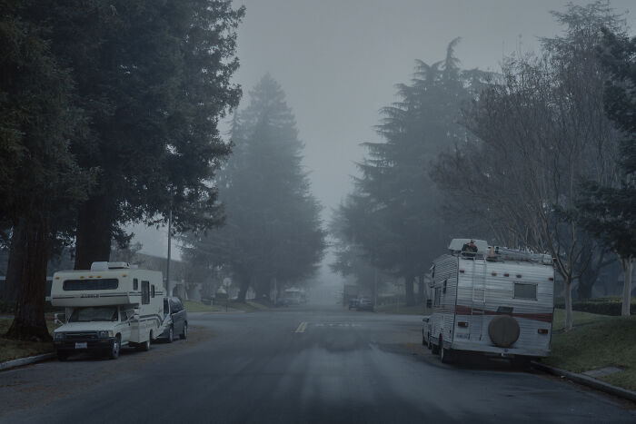 Foggy suburban street with parked RVs, capturing the quiet poetry of disconnection.