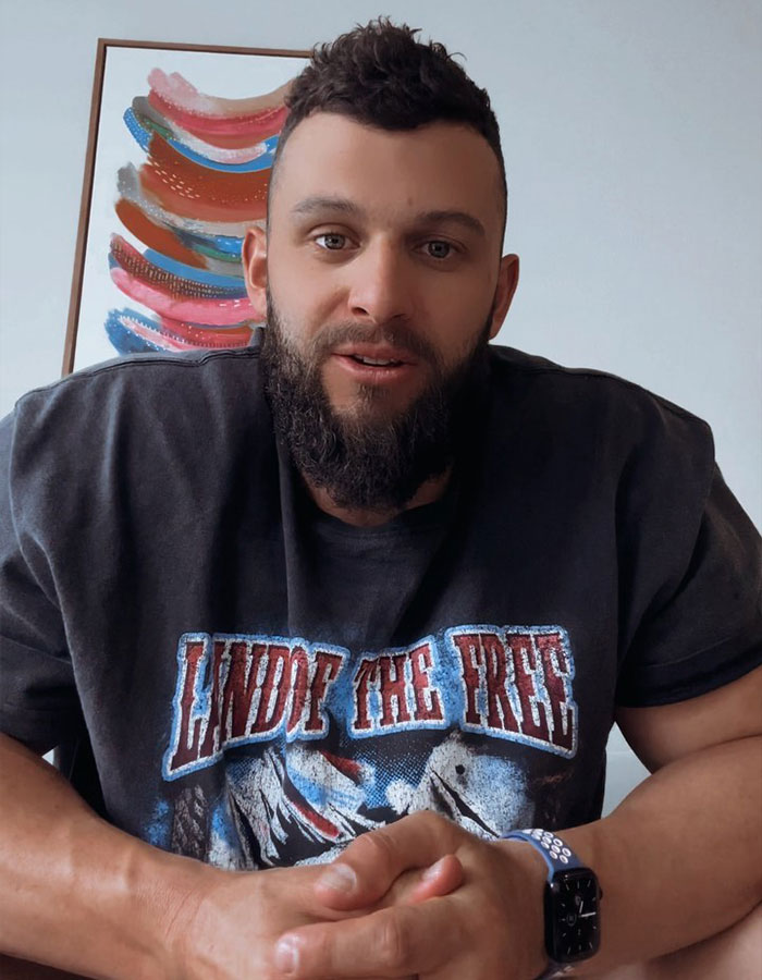 Man in a graphic tee discussing boundaries at bachelorette parties, with colorful art in the background.