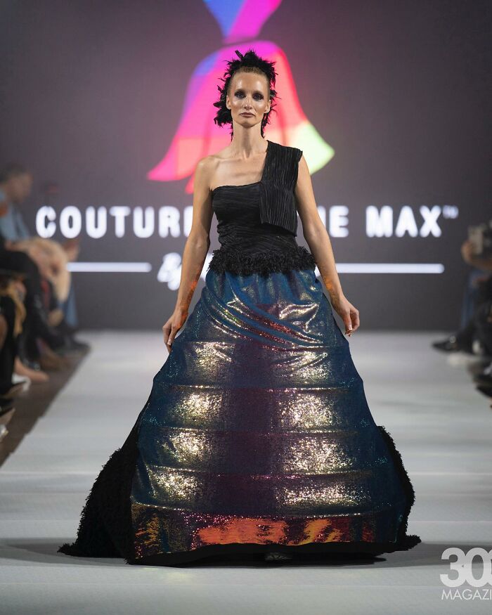 Model in a dazzling, colorful dress on runway, showcasing fashion prodigy's design.