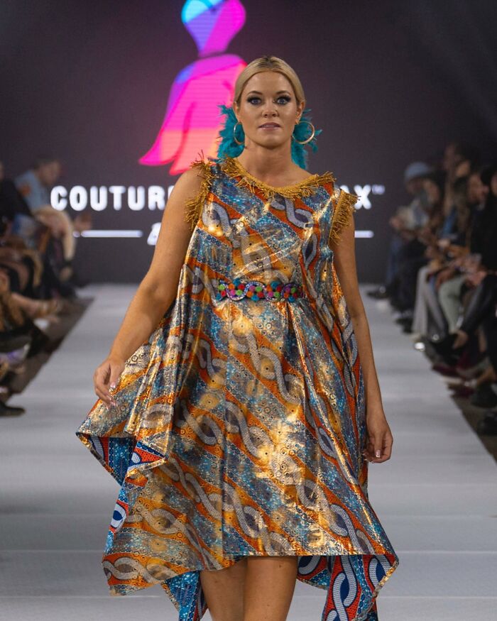 Model wearing a colorful dress designed by an 8-year-old fashion prodigy at a runway show.