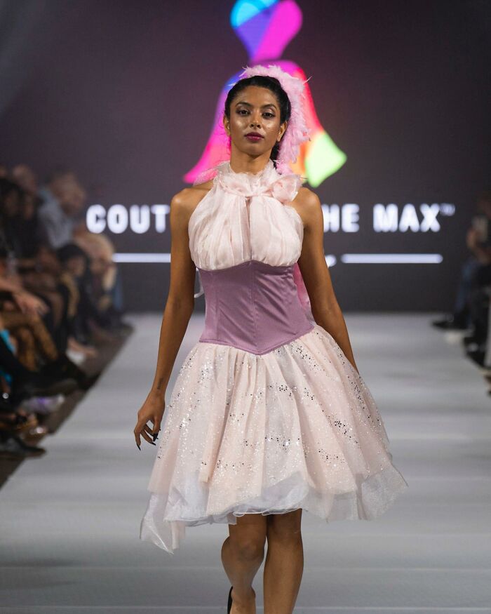 Model walks runway in a dress designed by an 8-year-old fashion prodigy, featuring sparkly pink and white fabric.