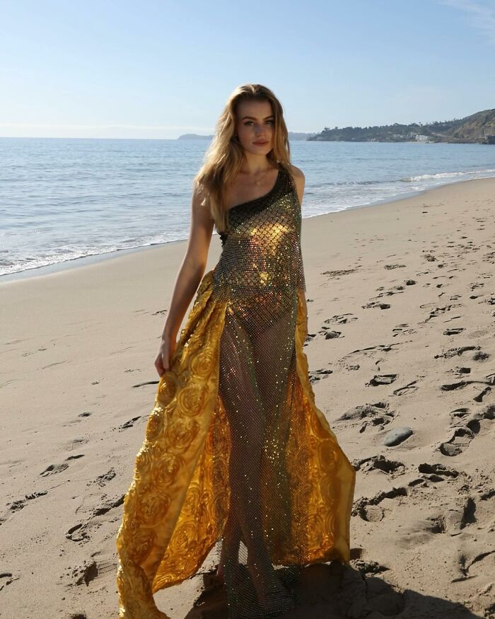 Fashion prodigy design: a model in a golden dress on a beach runway.