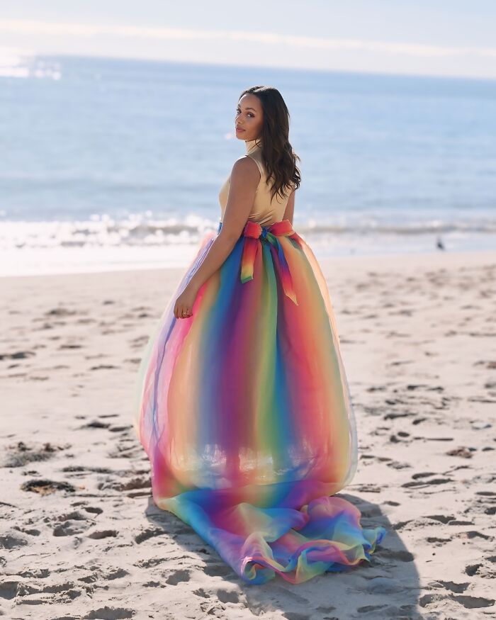 Fashion prodigy design: Woman in a colorful rainbow dress on the beach, showcasing creative dress design.