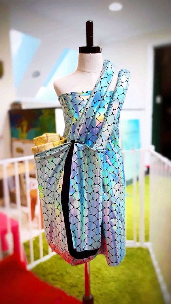 Holographic dress on mannequin by fashion prodigy, showcasing a creative pattern in a stylish room.