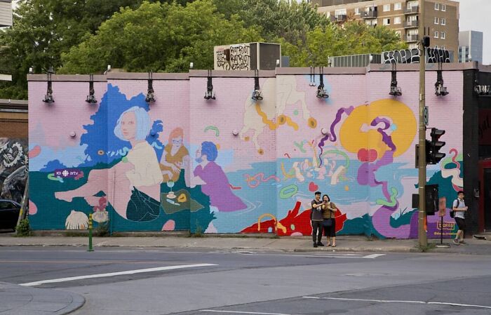 Colorful mural by Montréal artist transforming a dull wall into vibrant art, featuring abstract shapes and figures.