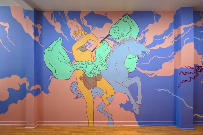 Colorful mural by Montréal artist, featuring a mythical figure on horseback against a vibrant blue and pink background.