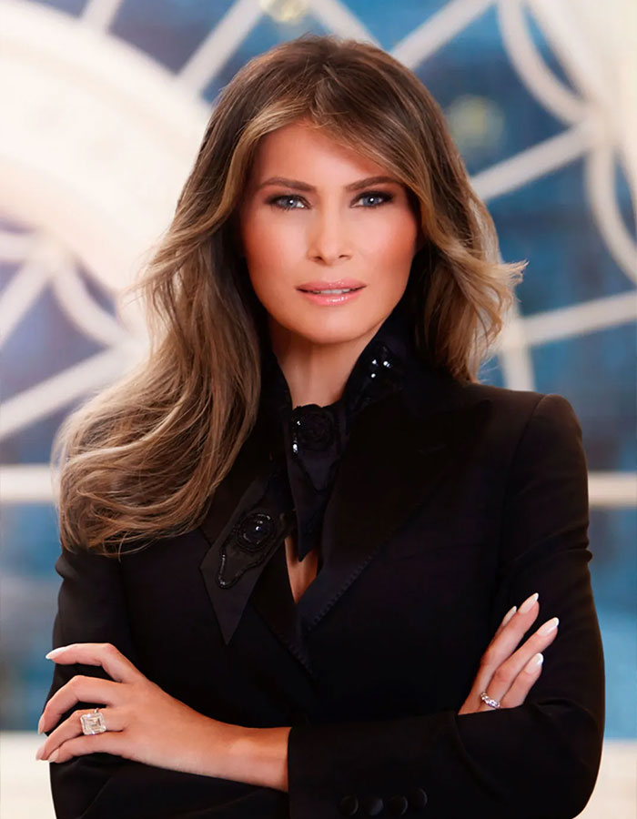 Woman in a formal black outfit with arms crossed against a blue decorative background. Freelance Magician theme.