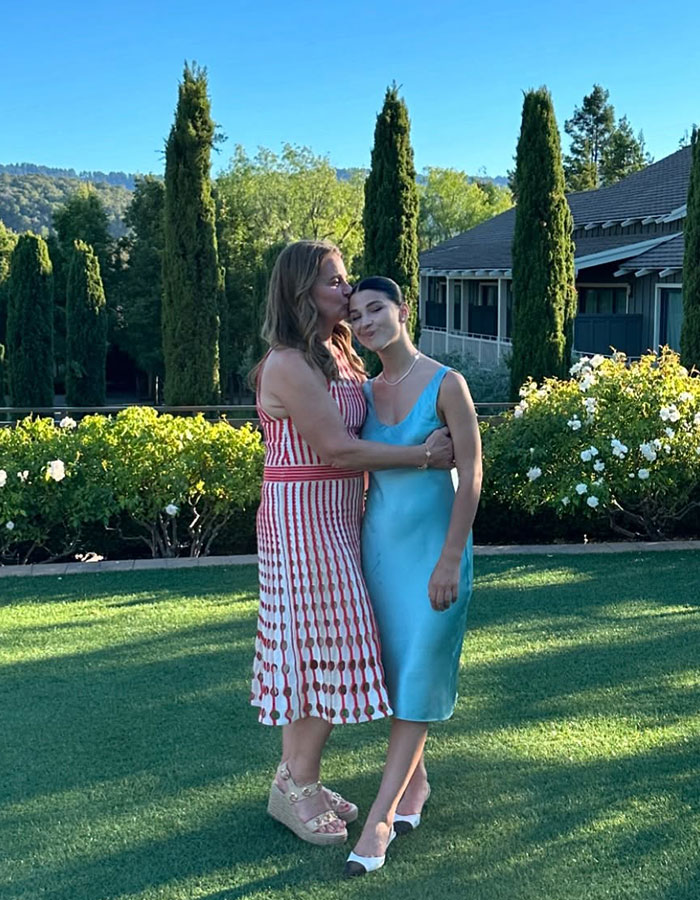 Two women embracing on a lawn, surrounded by greenery, related to Epstein Island topic discussion.