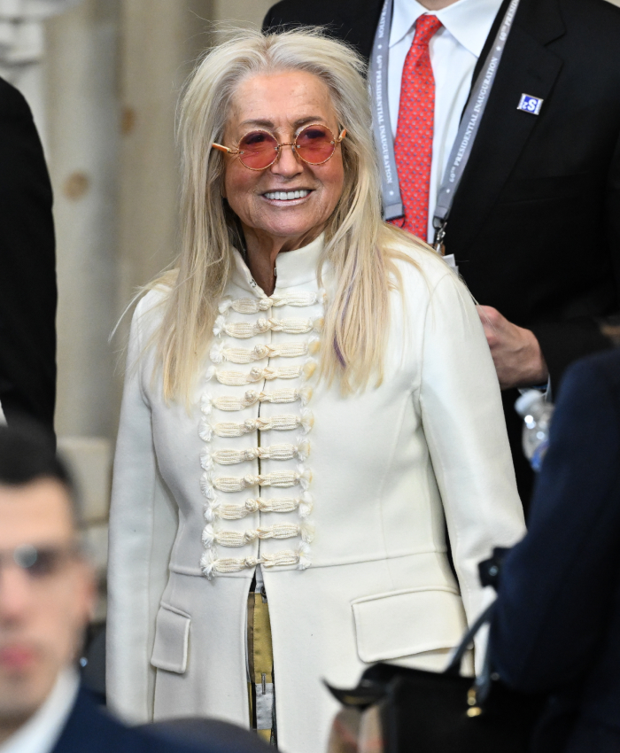 Woman in a white coat with sunglasses at presidential inauguration, showcasing controversial fashion choice.