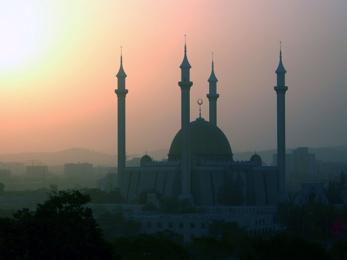 Silhouette of a mosque against a sunset sky, showcasing stunning natural phenomena.