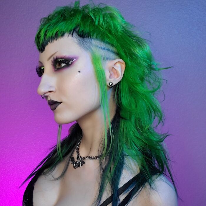 Green mullet hairstyle with vibrant makeup, featuring daring eye and lip colors.